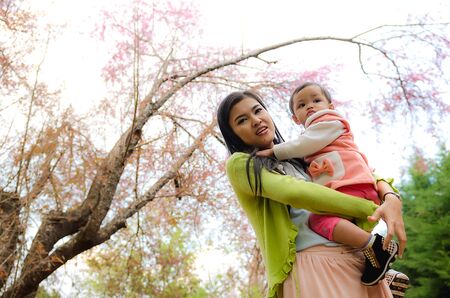Happy young mother playing with little daughter in park at chiangmai province in  thailand.