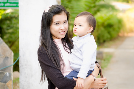 The child on a shoulder by mother to very happy. at garden in thailand.の写真素材