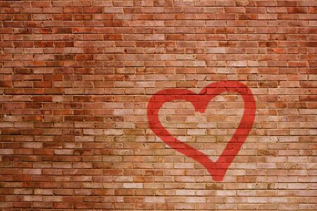 A battered brick wall with a sprayed red heart in spotlight の写真素材