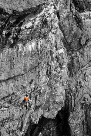 A climber clad in bright orange colour on a B&W rock, good background for の写真素材