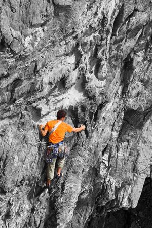 A climber clad in bright orange colour on a B&W rock, good background for の写真素材