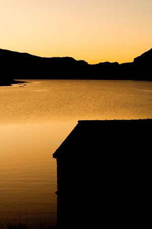 A boat shed silhouette at sunrise at Llyn Ogwen, Walesの写真素材
