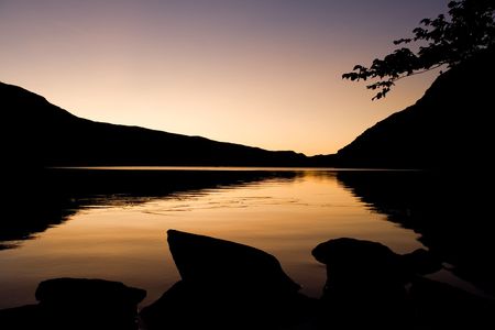 A romantic sunrise with silhouete of boulders and mountains surrounting Llyn Ogwen in Snowdonia, Walesの写真素材