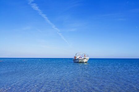 Motor boat on clear water with blue sky in backgroundの写真素材