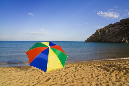 A colourful beach umbrella on an empty Tsambika beach on Rhodes Island, Greeceの写真素材