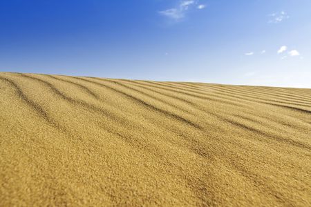 Background of golden sand dune and blue skyの写真素材