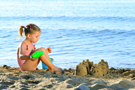 Smiling toddler girl playing with her toys at beachの写真素材