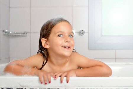 Girl playing with water and foam in a bathtub