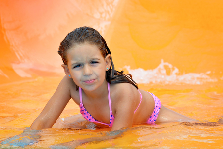 Real adorable toddler girl enjoying her summer vacation on waterslide at aquaparkの写真素材