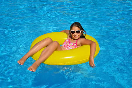 Real adorable girl relaxing in swimming pool, summer vacation concept