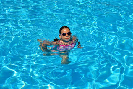Real adorable girl relaxing in swimming pool, summer vacation conceptの写真素材