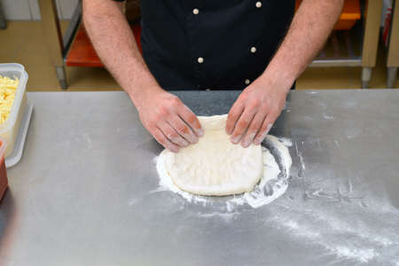 The process of making pizza, closeup hand of chef baker making pizza at kitchen.の写真素材
