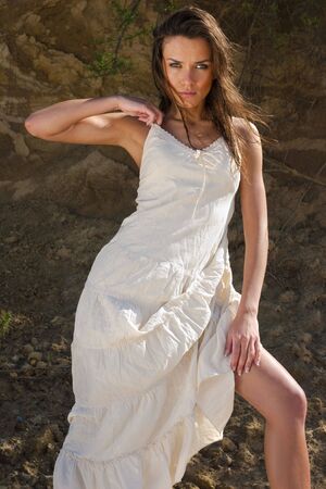 Young woman in white dress against the cliffの写真素材
