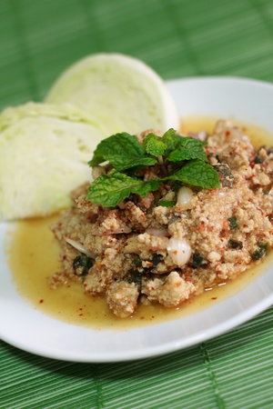 Thai Spicy Minced Pork Salad on White Dish and Green Plate Matの写真素材