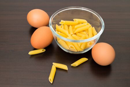 egg and maccheroni in cup on wood backgroundの写真素材