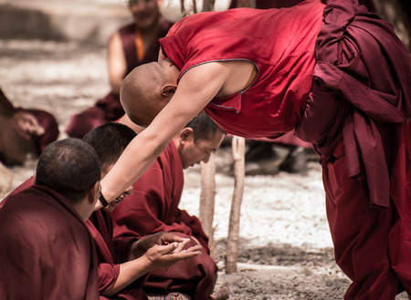 LHASA, TIBET - MAY 2016 - A senior monk listens to his fellow monks argument in a debate at Sera monastery, Lhasa, Tibet. The debate happens in the monastery courtyard. It is open to the public.のeditorial素材