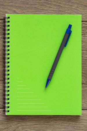 Green notebook on wooden deskの写真素材