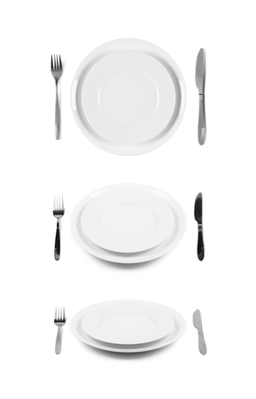 Two stacked white plates with fork and knife  Isolated on white  Three angles of view の写真素材