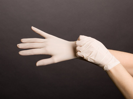 Female hands putting on latex gloves on dark backgroundの写真素材
