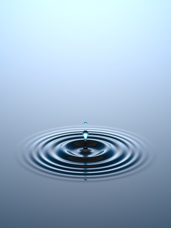 Water drop falling into water surfaceの写真素材