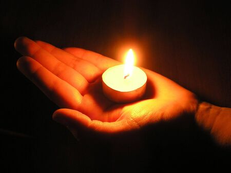 On a photo a candle which on a palm of the person. A photo on a dark background. The photo is made in Ukraine.   の写真素材