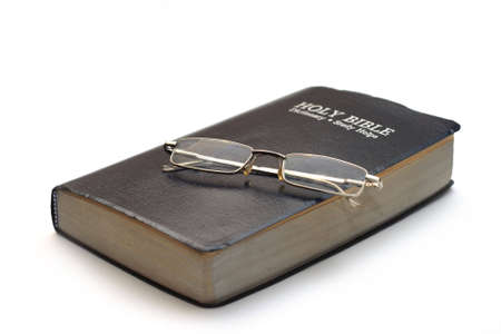 bible with folded reading glasses isolated on white