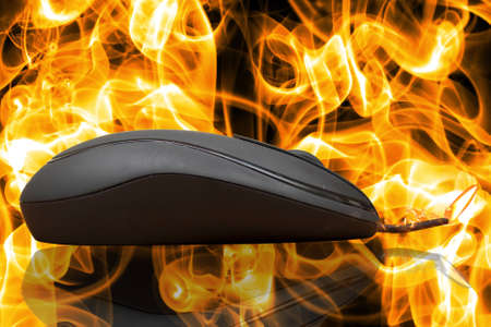 computer mouse with a burning cable on a background of fireの写真素材
