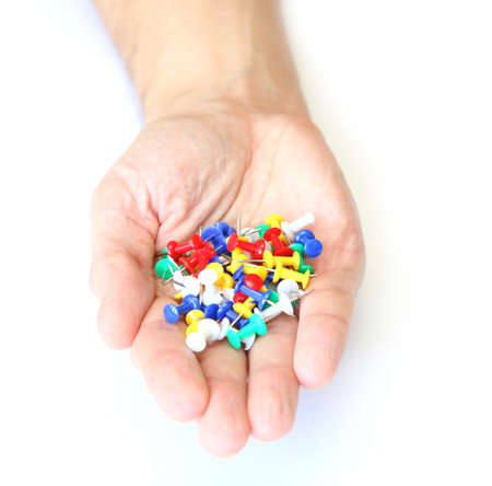 Hand with colored pushpin on a white background