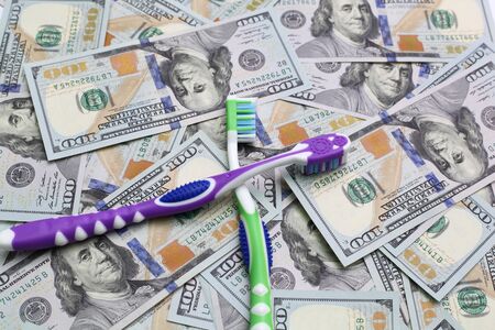 two toothbrushes on the background of dollar billsの写真素材