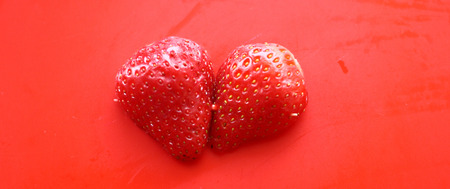 two pieces of strawberries on a red backgroundの写真素材