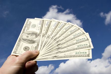 Money in hand  isolated on sky backgroundの写真素材