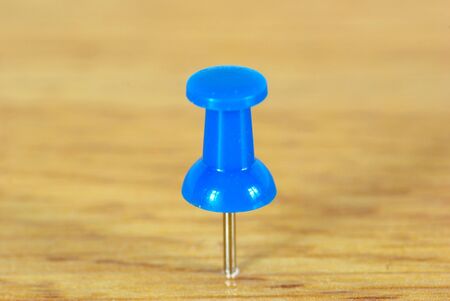 blue push pin isolated on wooden backgroundの写真素材
