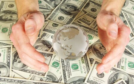 Hands holdings a globe on a money backgroundの写真素材