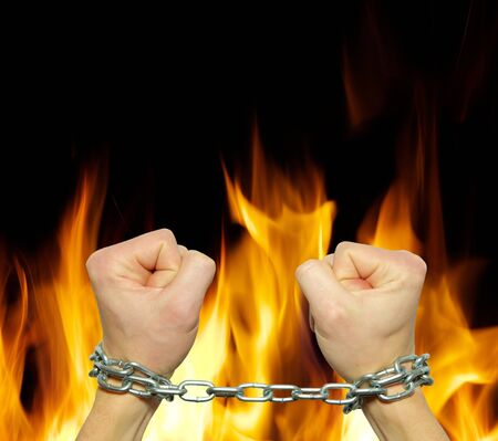Hands in chains on a fire  background       