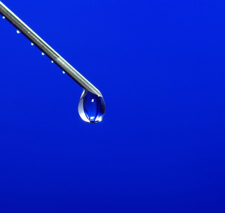 Drop on syringe needle macro on blueの写真素材