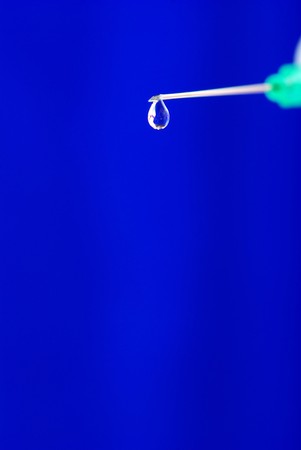 Drop on syringe needle macro on blueの写真素材