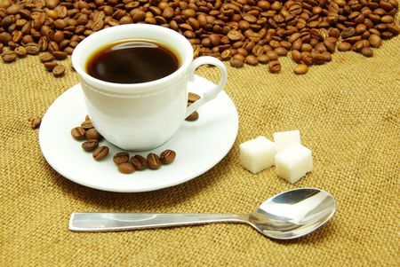 White cup of coffee on beans and sack background