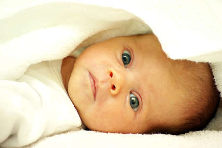 baby looking out from under blanket