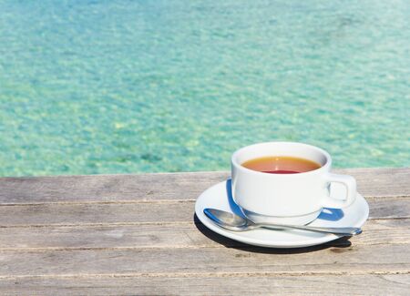 A cup of tea on table with sea at the backgroundの写真素材
