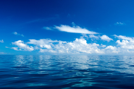 clouds on blue sky over calm sea with sunlight reflectionの写真素材