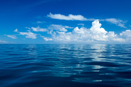 clouds on blue sky over calm sea with sunlight reflectionの写真素材
