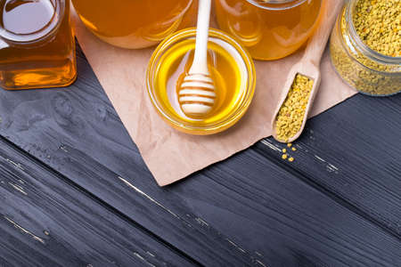 Honey with wooden honey dipper on wooden table