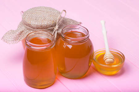 Honey with wooden honey dipper on wooden tableの写真素材