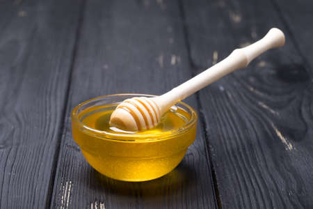 Honey in jar with honey dipper on wooden backgroundの写真素材