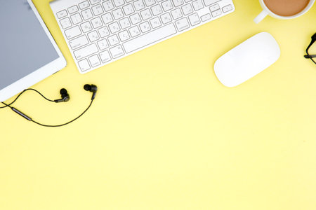workspace with tablet, keyboard, coffee cup and eyeglasses copy space on yelow background. Top view.
