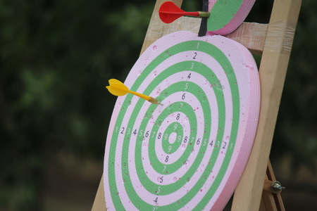 Playing darts on an apple-shaped dart board outdoorの写真素材