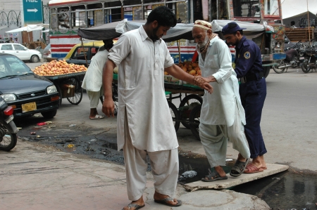 KARACHI/PAKISTAN_   Pakistani mature males helping a eldlery blind man by passing dirty water 16 Sept. 2012       のeditorial素材