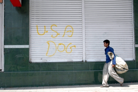KARACHI/PAKISTAN_ Pakistani male passing by closed shop door and USA Dog sign has been written unknown person 22 Sept. 2012          のeditorial素材