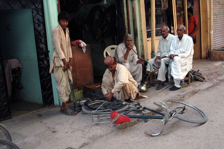 KARACHI/PAKISTAN_ Pakistani struggle for daily life male own Wafash cycle works and senior smoking water pipe ,since sneior has no plce to go in their free time there are no senior home, most  of senior spend time on shop or in street Azam basti 26 Sept. のeditorial素材