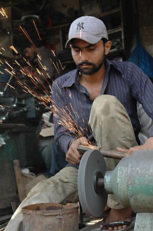KARACHI/PAKISTAN_ Pakistani shop keeper  sharping knives preparing for Holy qarbani slaughtering lambs and other animals during holy  eid season 17 Oct. 2012         のeditorial素材